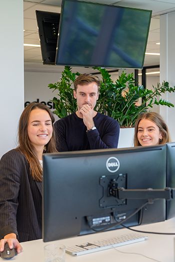 Drie collega's analyseren scherm met marketingdata tijdens overleg over de klantreis